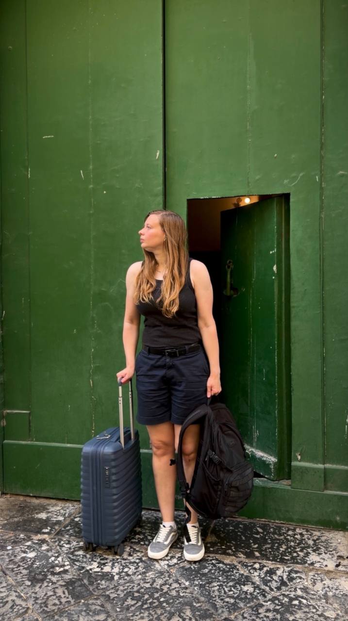 Anastasia traveling with a suitcase in front of a green door